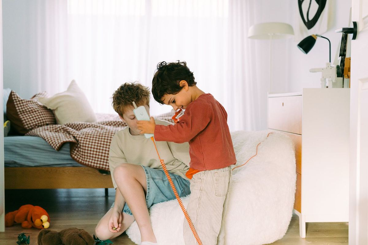 Two young brothers sharing the Waffle Home handset on a beanbag in their bedroom.