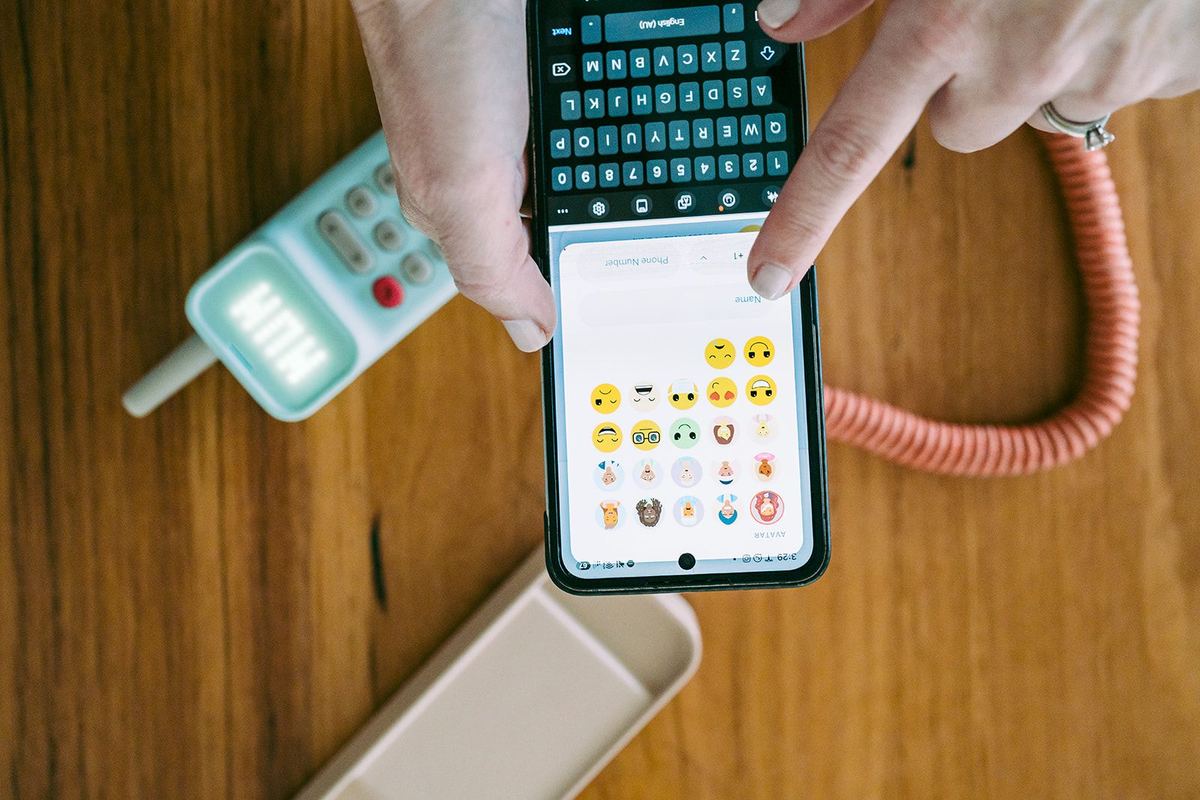 A parent adding a contact to a child's Waffle Home phone from the companion app, the handset on the table beside them.